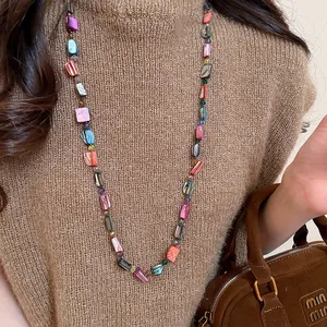 Detail shot of a bohemian multi-color beaded long necklace with shell slice pendants