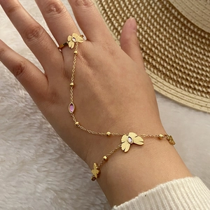 Dettaglio della catena a mano a farfalla dorata con gemme viola indossata a mano
