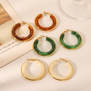 Close-up of retro resin hoop earrings in amber brown, dark green, and cream white