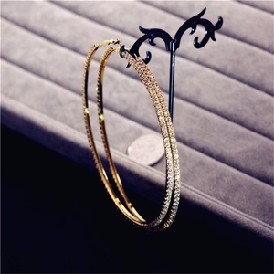 Macro shot of large golden hoop earrings with clear crystal rhinestones on display