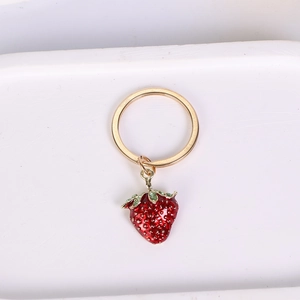 Close-up of golden zinc alloy strawberry keychain with red fruit and green leaves detail