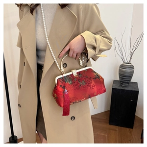 Detail of red vintage floral brocade bag with pearl chain strap and silk tassel accent