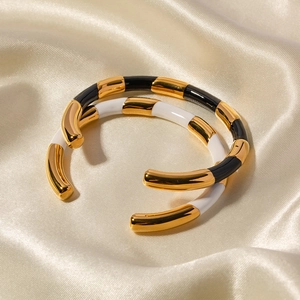 Detail of C-shaped titanium steel bracelets with black and white enamel inlays
