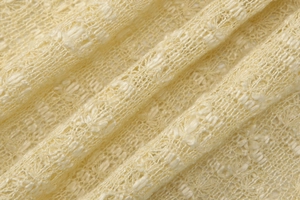 Close-up of cream knit fabric with a semi-transparent hollow texture and soft drape