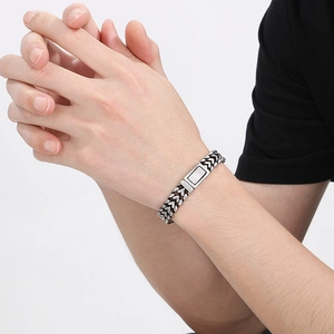 Dettaglio del bracciale vintage in acciaio inossidabile intrecciato sul polso maschile