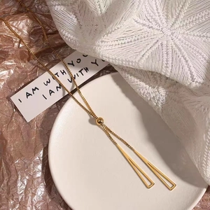 Close-up of gold Y-shaped necklace with hollow triangle pendants and slider buckle