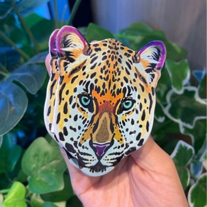 Detailed view of an acrylic leopard head hair claw with colorful tiger spots and green eyes