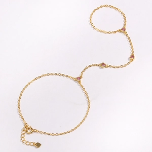 Close-up of 18k gold chain hand harness featuring delicate pink heart-shaped gemstones