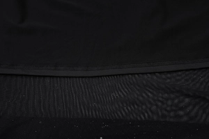 Détail du tissu en maille noire cousu au tulle pailleté avec une couture passepoilée