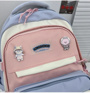 Detail of multi-color nylon backpack featuring cartoon pins and transparent brand label