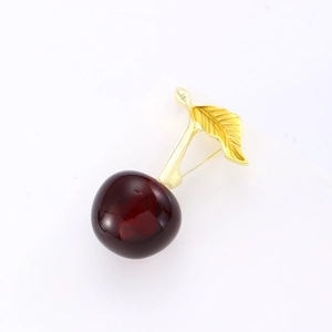 Broche cerise élégante avec fruits rouge foncé et feuilles dorées sur socle blanc