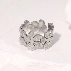 Polished silver stainless steel floral open ring with flower petal design on a stone surface