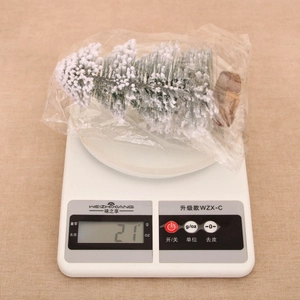 Detailed view of mini flocked Christmas tree with wood base on digital scale weighing 21g