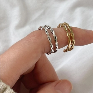 Detailed view of layered silver and gold twisted rope open rings on a model's finger