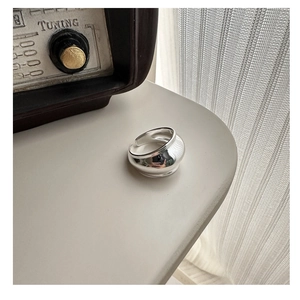 Modern thick polished silver ring on a minimalist desk with soft lighting