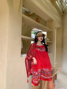 Detailed view of red ethnic shawl with geometric embroidery and tassels in a desert setting