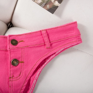 Détail du short en jean rose fuchsia avec boutons métalliques et tissu texturé