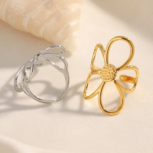 Detailed macro view of retro gold and silver floral open rings on a textured surface