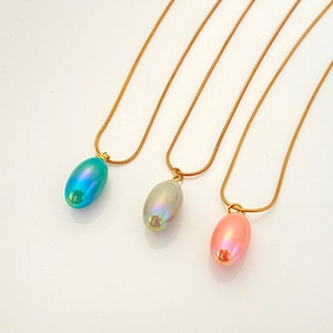 Macro shot of three colorful pear-shaped teardrop pendants on sleek gold snake chains