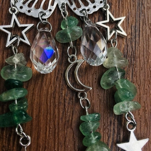 Detailed shot of silver crescent moon and green crystal beads suncatcher on dark wood