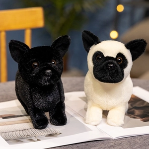 Standing black and bicolor French Bulldog plush toys on a magazine in cozy room decor
