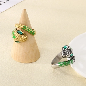 Detailed shot of gold and silver snake rings with emerald eyes on a minimalist display