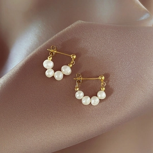 Detailed close-up of S925 silver needle Baroque pearl earrings on champagne silk fabric