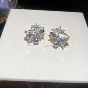 Macro shot of silver bow clip earrings with sparkling zircons and grey faux pearls