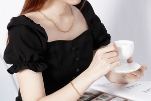 Model wearing gold paperclip link necklace and bracelet set with elegant black dress