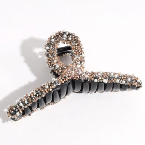 Detailed closeup of a black rhinestone pearl hair claw clip, sparkling crystals texture.