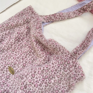 Gros plan du cabas en fausse fourrure léopard rose avec étiquette dorée et doublure mauve