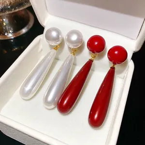 Elegant gold drop earrings with white pearl and vintage red pendants in a white box