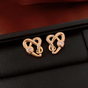 Macro shot of gold plated heart snake earrings featuring zironia and detailed metal texture