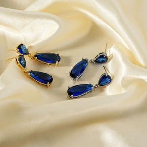 Vintage water-drop cubic zirconia earrings with gold and silver settings on silk backdrop