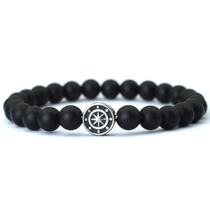 Detail view of matte black beaded bracelet with silver starburst metal charm