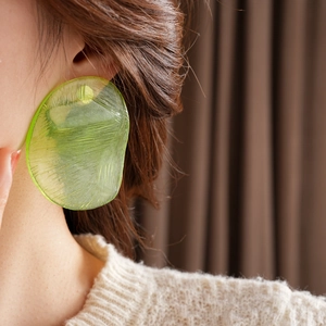 Close-up of green translucent resin earring with irregular texture on a model