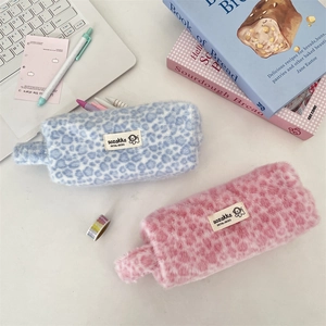 Detail of plush leopard print makeup pouches in blue and pink on a creative desk