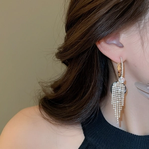 Close-up of elegant long tassel drop earrings with sparkling crystals on golden metal