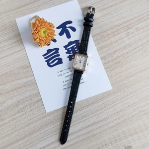 Close-up of vintage square watch with Roman numerals and black crocodile leather strap