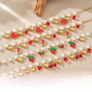Detailed shot of pearl bracelet featuring red enamel strawberry and watermelon charms