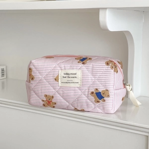 Detailed view of pink striped quilted cosmetic bag with cute bear pattern and woven label