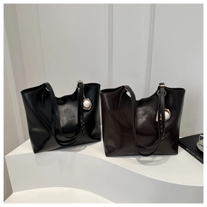 Close-up of large black and brown tote bags in glossy leather with baseball charms