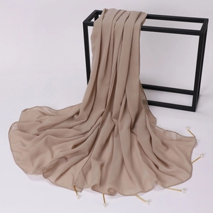 Detail of light beige chiffon shawl featuring elegant gold pins with pearl accents