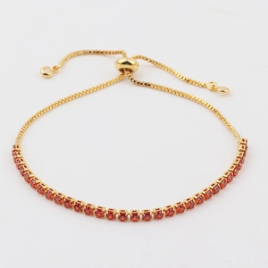 Detail of gold-plated box chain bracelet with adjustable sliding clasp and red zircons