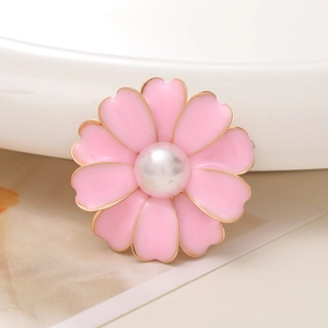 Detailed macro view of a pink enamel flower charm with golden edges and a central pearl