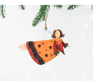 Close-up of a hand-painted wooden angel ornament with red heart hanging on a pine branch