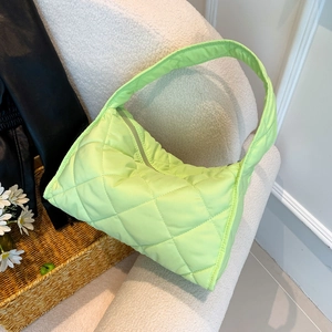Detailed close-up of neon green quilted nylon pillow bag on a soft beige background