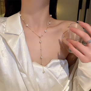 Detailed view of elegant gold Y-shaped necklace with white pearls on a female model