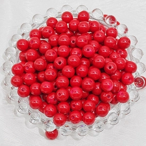 Close-up of bright red round glass beads with holes for DIY jewelry making and crafts