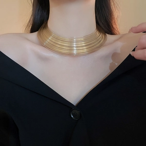 Close-up of model wearing gold layered metallic collar necklace in minimalist style